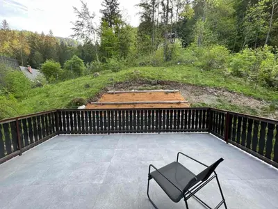 a chair sitting on a patio with a fence at Our Forest House in Tržič