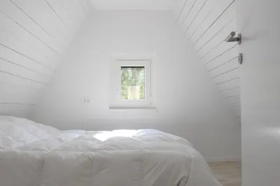 a white bed in a white room with a window at Our Forest House in Tržič