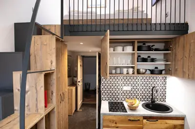 a small kitchen with wooden cabinets and a staircase at Becycle Sustainable stay and travel in Maribor