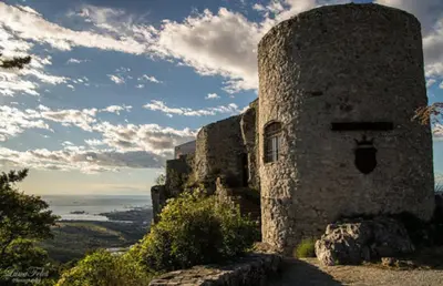 a stone building on top of a hill with the ocean at Hisa dobrega pocutja in Kozina