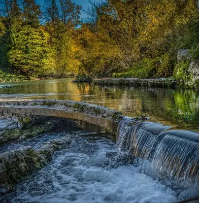 a stone bridge over a river with a waterfall at Apartments Jez in Slappe dʼIdria