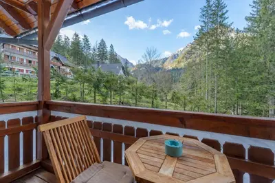 a wooden table and chairs on a balcony with a view at Apartma Gaja in Kranjska Gora