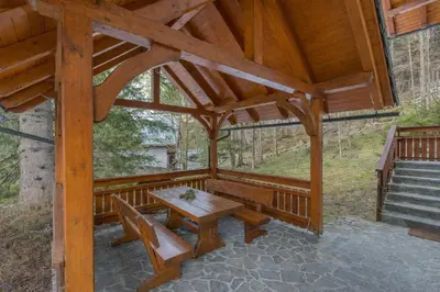 a wooden pavilion with a wooden table and benches at Apartma Gaja in Kranjska Gora