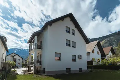 a white house with mountains in the background at Julian Manor apartments in Bovec