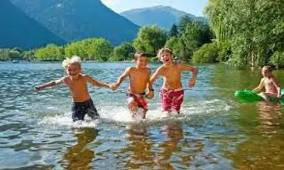 a group of children walking in the water at Hillside Bio Resort Apartment with Mountain View in Prebold