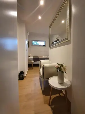 a living room with a table and a chair and a mirror at Počitniška hiša Grube z wellnesom in Puconci