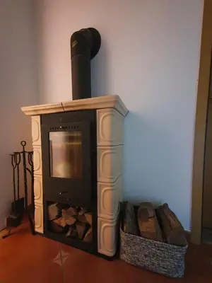 a fireplace with a wood stove in a room at Počitniška hiša Grube z wellnesom in Puconci