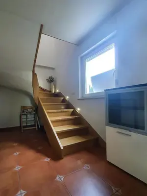a living room with a staircase and a television at Počitniška hiša Grube z wellnesom in Puconci