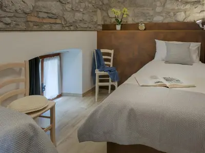 a bedroom with a bed with a book on it at Apartmaji in sobe Odlična hiša Štanjel in Štanjel