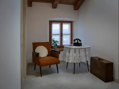 a living room with a table and a chair at Apartmaji in sobe Odlična hiša Štanjel in Štanjel