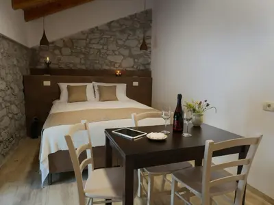 a bedroom with a bed and a table and chairs at Apartmaji in sobe Odlična hiša Štanjel in Štanjel