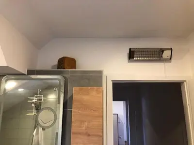 a bathroom with a shower and a fan on the wall at Apartma na hüti in Radenci