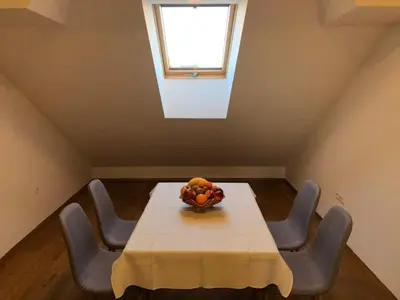 a table with chairs and a vase of fruit on it at Apartma na hüti in Radenci