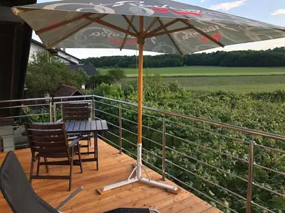 a table and chairs under an umbrella on a deck at Apartma na hüti in Radenci