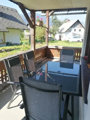 a table and chairs on the back porch of a house at Apartment V&N, LAKE BOHINJ in Bohinj