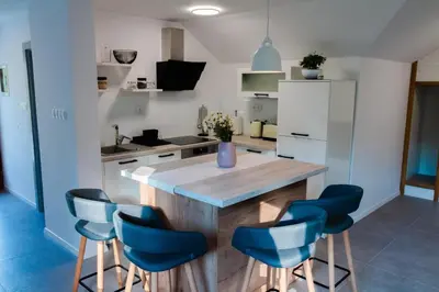 a kitchen with a wooden island with blue chairs at Vineyard cottage Radulja in Smarjeske Toplice