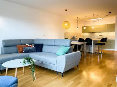 a living room with a blue couch and a kitchen at Lakeview Villa Bled in Bled