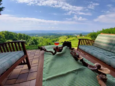 a patio with two benches and a table with a view at Oldhouse Knezovo in Sromlje