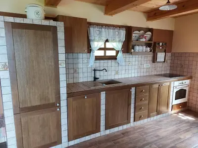 a kitchen with wooden cabinets and a sink and a window at Oldhouse Knezovo in Sromlje