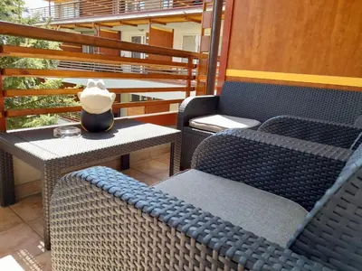 a patio with two chairs and a table with a vase on it at Honey Apartment in Moravske Toplice