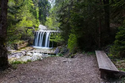 a wooden bench sitting in front of a waterfall at Sobe v Gozdu in Gozd Martuljek