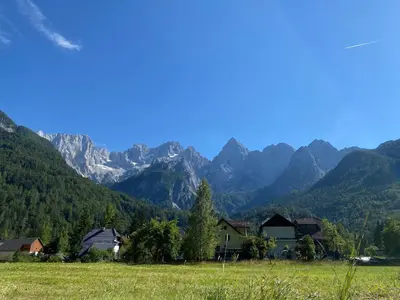 a green field with mountains in the background at Sobe v Gozdu in Gozd Martuljek