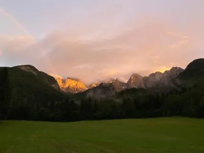 a rainbow in the mountains with a green field at Sobe v Gozdu in Gozd Martuljek