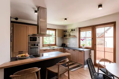 a kitchen with wooden cabinets and a counter with chairs at Tromeja in Rateče
