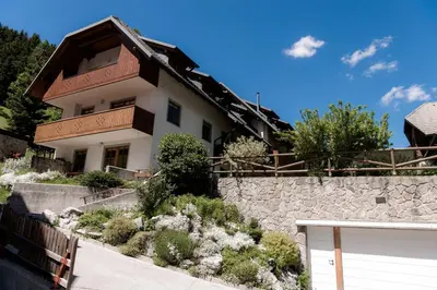 a house with a stone wall and a fence at Tromeja in Rateče