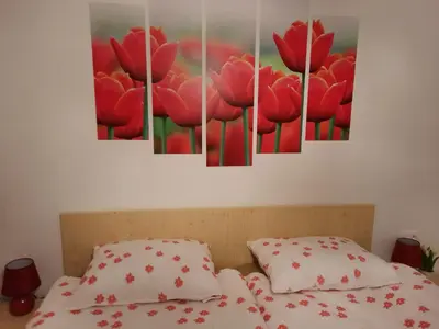 a bedroom with red tulips paintings on the wall at Apartma Rožle in Mojstrana