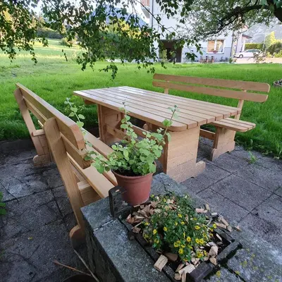 a wooden picnic table and bench with a potted plant at Apartma Rožle in Mojstrana