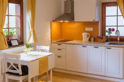 a kitchen with white cabinets and a table with chairs at Frida's Old House in Bled
