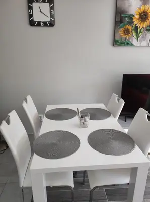a white dining room table with white chairs and a clock at Apartment Mojca in Bovec
