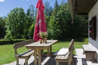 a picnic table with a red umbrella and two benches at Mountain house MINKA in Srednja Vas v Bohinju