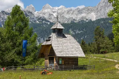 a small building in a field with mountains in the background at Mountain house MINKA in Srednja Vas v Bohinju