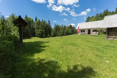 a field with a sign in the grass next to a barn at Mountain house MINKA in Srednja Vas v Bohinju