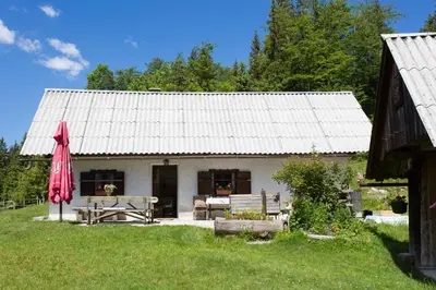 a white house with a table and a red umbrella at Mountain house MINKA in Srednja Vas v Bohinju