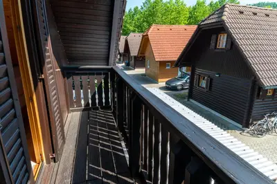 a balcony with a wooden fence and some houses at Bella Mura Nature Chalet I27 in Podčetrtek