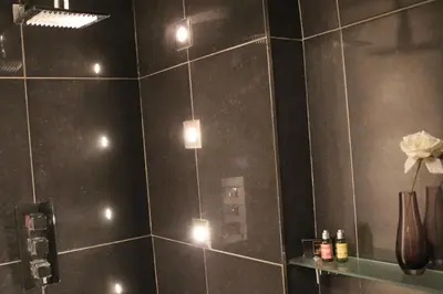 a bathroom with a black tiled wall with lights at The Lodge in Rogaška Slatina