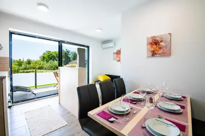 a dining room with a table and chairs and a window at Apartmaji BANONIA in Veržej