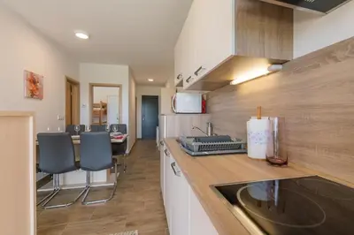 a kitchen with a sink and a counter with chairs at Apartmaji BANONIA in Veržej