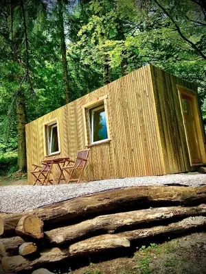 a small wooden cabin in the woods with a table and chairs at Skalca in Kamniška Bistrica
