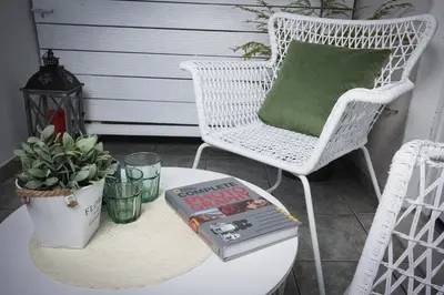 a white wicker chair and a table with a book at Lakefront Bled - Rooms & Apartments in Bled