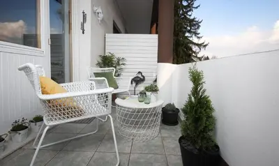 a patio with white chairs and a table with plants at Lakefront Bled - Rooms & Apartments in Bled