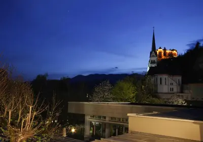 a building with a church with a steeple at night at Lakefront Bled - Rooms & Apartments in Bled