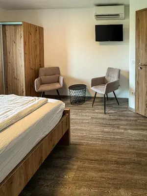 a bedroom with a bed and two chairs and a tv at Rooms Minka in Kamna Gorica