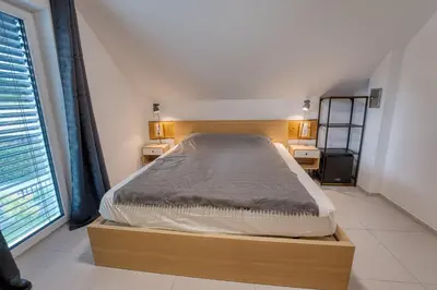 a bedroom with a bed with a wooden frame and a window at Rooms Minka in Kamna Gorica
