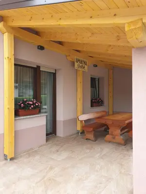 a wooden porch with a picnic table and a sign at Apartma Patrik in Kobarid