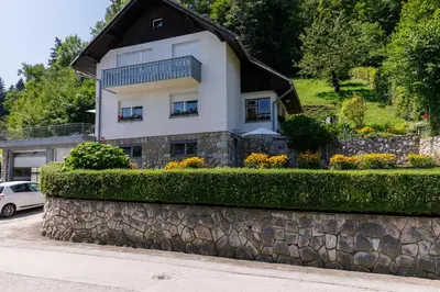 a house on a hill with a stone wall at Apartment Mavrica Bled in Bled