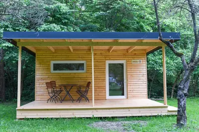 a wooden cabin with a table on a deck at Kamp na Otoku - Ljubno ob Savinji in Ljubno